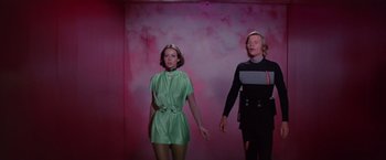 Movie still from “Logan's Run” (1976), directed by Michael Anderson – A woman and a man standing next to each other in front of a pink wall; Medium shot, Low angle