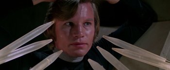 Movie still from “Logan's Run” (1976), directed by Michael Anderson – A man is holding a bunch of knives in front of his face; Close Up shot, Low angle
