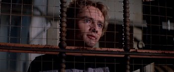 Movie still from “Logan's Run” (1976), directed by Michael Anderson – A man with blue eyes looking out of a cage; Close Up shot, Low angle