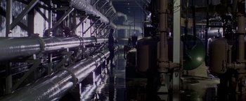 Movie still from “Logan's Run” (1976), directed by Michael Anderson – A person walking in a room next to pipes; Extreme Wide shot, High angle