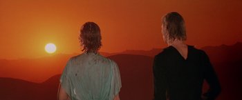 Movie still from “Logan's Run” (1976), directed by Michael Anderson – Two people are standing in front of a sunset; Medium shot, Low angle