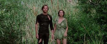 Movie still from “Logan's Run” (1976), directed by Michael Anderson – A man and a woman standing next to each other in front of tall grass; Medium shot, Low angle