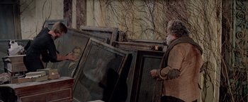 Movie still from “Logan's Run” (1976), directed by Michael Anderson – An old man standing in front of a bunch of paintings; Medium shot, Over the shoulder angle