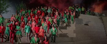 Movie still from “Logan's Run” (1976), directed by Michael Anderson – A large group of people dressed in red and green; Extreme Wide shot, High angle