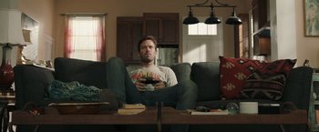 A man sitting on top of a couch holding a remote control