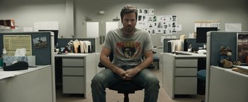 A man sitting on top of an office chair in an office