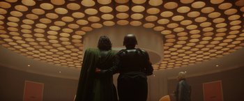 Movie still from “Loki” (2021), created by Michael Waldron – A couple of people standing next to each other in a room; Wide shot, Low angle
