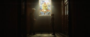Movie still from “Loki” (2021), created by Michael Waldron – A man and a woman standing in front of a stained - glass window; Wide shot, Low angle