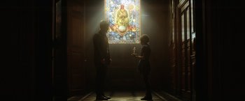 Movie still from “Loki” (2021), created by Michael Waldron – A man and a woman standing in front of a stained - glass window; Wide shot, Low angle