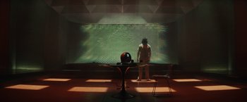 Movie still from “Loki” (2021), created by Michael Waldron – A person standing in front of a large screen; Wide shot, High angle