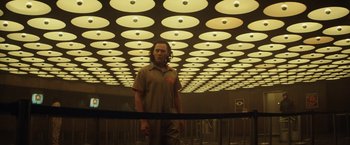 Movie still from “Loki” (2021), created by Michael Waldron – A man standing in front of a room with lights on the ceiling; Wide shot, Low angle