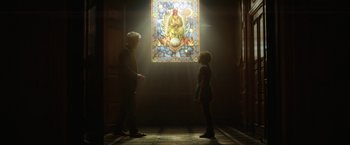 Movie still from “Loki” (2021), created by Michael Waldron – A man and a woman standing in front of a stained - glass window; Wide shot, Low angle