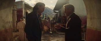 Movie still from “Loki” (2021), created by Michael Waldron – Two men in suits talking to each other in the street; Medium shot, Over the shoulder angle