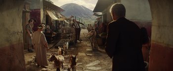 Movie still from “Loki” (2021), created by Michael Waldron – A group of people walking down a street with goats; Wide shot, Over the shoulder angle