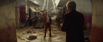Movie still from “Loki” (2021), created by Michael Waldron – A man in a suit and tie standing next to another man in a suit and tie; Extreme Wide shot, Over the shoulder angle