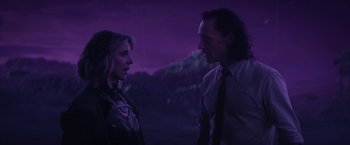 Movie still from “Loki” (2021), created by Michael Waldron – A man and a woman standing next to each other in front of a purple background; Medium shot, Over the shoulder angle
