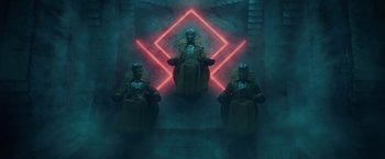 Movie still from “Loki” (2021), created by Michael Waldron – A group of people sitting on chairs in a room with neon lights; Extreme Wide shot, Low angle