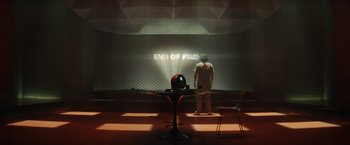 Movie still from “Loki” (2021), created by Michael Waldron – A man standing in front of a table in a dimly - lit room; Extreme Wide shot, Low angle