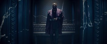 Movie still from “Loki” (2021), created by Michael Waldron – A man standing in a dark room wearing a purple cape; Wide shot, Low angle