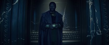 Movie still from “Loki” (2021), created by Michael Waldron – A man dressed in a costume holding a green apple; Medium shot, Low angle