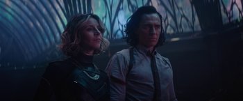 Movie still from “Loki” (2021), created by Michael Waldron – A woman and a man standing next to each other; Medium shot, Low angle