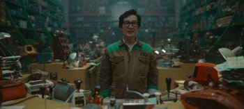 Movie still from “Loki” (2021), created by Michael Waldron – A man standing in front of a table full of tools; Medium shot, Over the shoulder angle