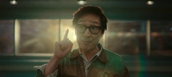 Movie still from “Loki” (2021), created by Michael Waldron – A man with glasses is pointing to his head; Close Up shot, Low angle