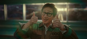 Movie still from “Loki” (2021), created by Michael Waldron – A man giving two thumbs up while wearing glasses; Close Up shot, Low angle