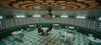 Movie still from “Loki” (2021), created by Michael Waldron – Two men sitting at a table in a restaurant; Extreme Wide shot, Overhead angle