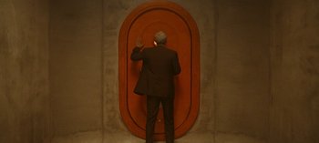 Movie still from “Loki” (2021), created by Michael Waldron – A man standing in front of an oval shaped door; Medium shot, High angle