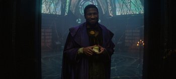 Movie still from “Loki” (2021), created by Michael Waldron – A man dressed in a purple robe and holding an apple; Medium shot, Low angle