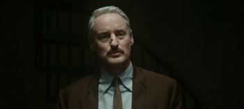 Movie still from “Loki” (2021), created by Michael Waldron – A person wearing a suit and tie; Close Up shot, Low angle