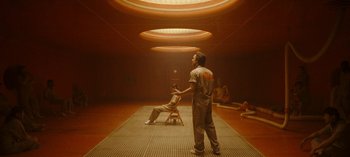 Movie still from “Loki” (2021), created by Michael Waldron – A man standing in front of another man sitting in a chair; Wide shot, Low angle