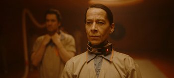 Movie still from “Loki” (2021), created by Michael Waldron – A man wearing a neck brace and a shirt; Close Up shot, Low angle