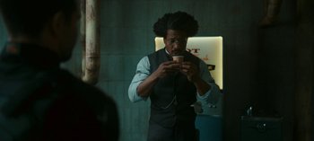 Movie still from “Loki” (2021), created by Michael Waldron – A man holding a cup in front of a mirror; Medium shot, Over the shoulder angle