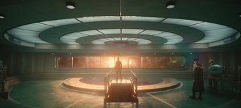 Movie still from “Loki” (2021), created by Michael Waldron – A person standing on a staircase in a building; Extreme Wide shot, Low angle