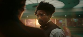 Movie still from “Loki” (2021), created by Michael Waldron – A man in a suit and tie looking at the camera; Close Up shot, Over the shoulder angle