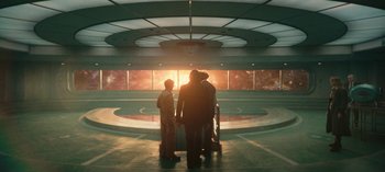 Movie still from “Loki” (2021), created by Michael Waldron – A group of people standing in front of a wall; Extreme Wide shot, High angle