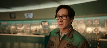 Movie still from “Loki” (2021), created by Michael Waldron – A man wearing glasses standing in front of a counter; Close Up shot, Over the shoulder angle