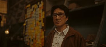 Movie still from “Loki” (2021), created by Michael Waldron – A man in a brown jacket standing in front of a wall covered with post - it notes; Close Up shot, Over the shoulder angle