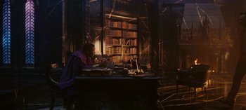 Movie still from “Loki” (2021), created by Michael Waldron – A man sitting at a desk in front of a book case; Wide shot, High angle