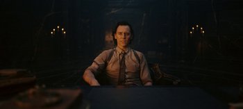 Movie still from “Loki” (2021), created by Michael Waldron – A man sitting in a chair in a dark room; Medium shot, Over the shoulder angle