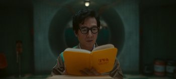 Movie still from “Loki” (2021), created by Michael Waldron – A man is reading a yellow book in a room; Close Up shot, Low angle