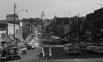 Movie still from “Lolita” (1962), directed by Stanley Kubrick – A black and white photo of a busy street; Extreme Wide shot, High angle