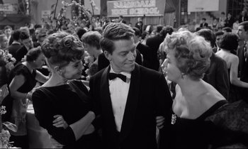 Movie still from “Lolita” (1962), directed by Stanley Kubrick – A man in a tuxedo standing next to two other people; Medium shot, Over the shoulder angle