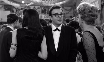 Movie still from “Lolita” (1962), directed by Stanley Kubrick – A man in a tuxedo standing next to other people; Medium shot, Over the shoulder angle