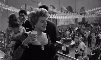 Movie still from “Lolita” (1962), directed by Stanley Kubrick – A black and white photo of a woman holding a plate of cake; Medium shot, High angle