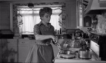 Movie still from “Lolita” (1962), directed by Stanley Kubrick – An older woman in an apron cooking in a kitchen; Medium shot, High angle