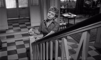 Movie still from “Lolita” (1962), directed by Stanley Kubrick – A woman sitting on top of a wooden railing; Medium shot, High angle