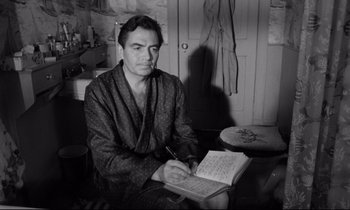 Movie still from “Lolita” (1962), directed by Stanley Kubrick – A black and white photo of a man writing in a notebook; Medium shot, High angle